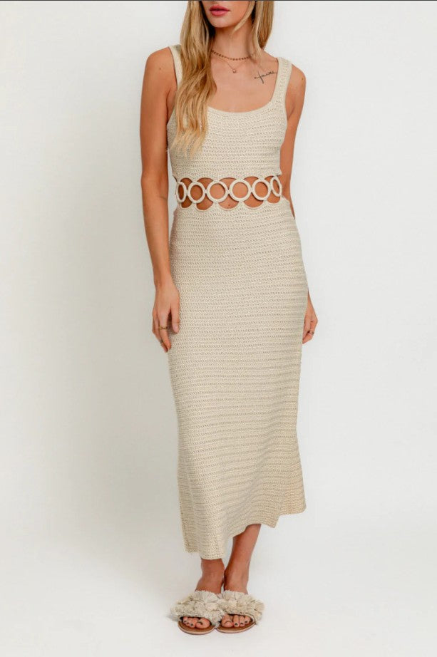 Woman wearing a beige sleeveless dress with cut-out design on a white background
