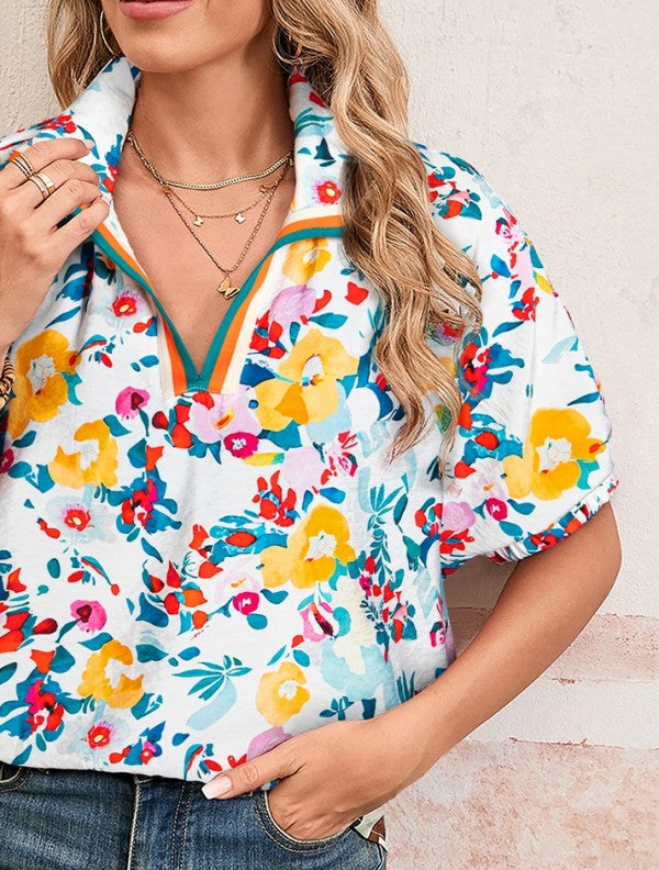 Woman wearing a colorful floral blouse with a neutral background