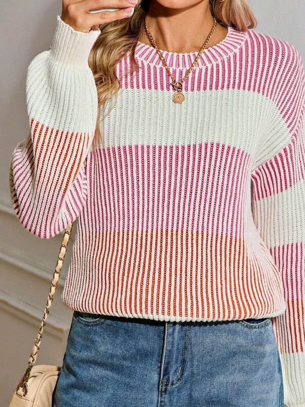 Person wearing a pink and white striped sweater with blue jeans and a beige handbag.