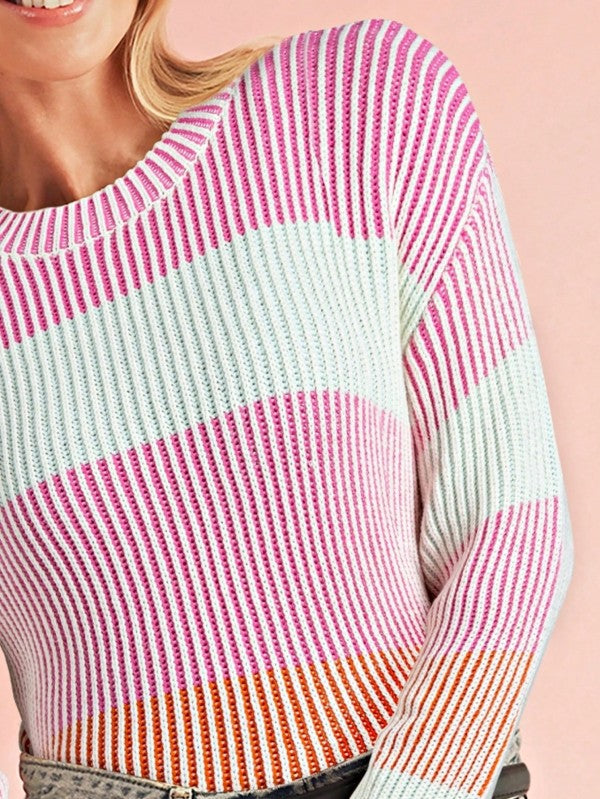 Close-up of a person wearing a colorful striped sweater on a light pink background