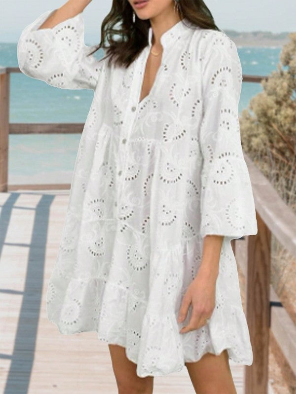 Woman wearing a white lace dress by a beach.