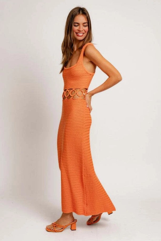 Woman wearing an orange dress with a belt on a white background
