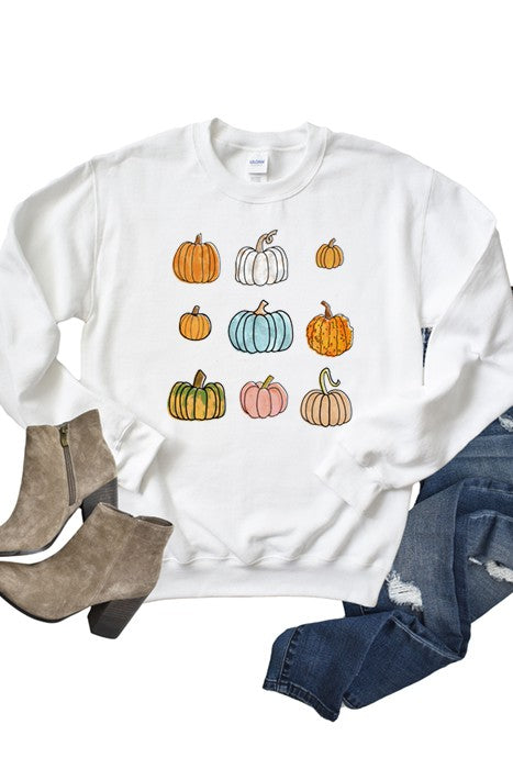 White sweatshirt with colorful pumpkin design, paired with brown boots and blue jeans on a white background.