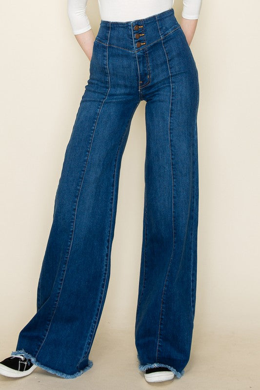 Blue bell-bottom jeans worn by a person on a beige background