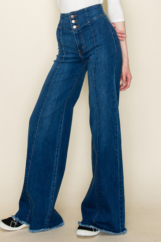 Blue flared jeans worn by a person on a beige background