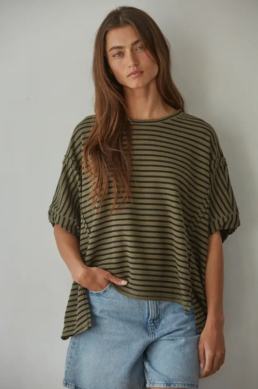Woman wearing a striped shirt and jeans against a plain background