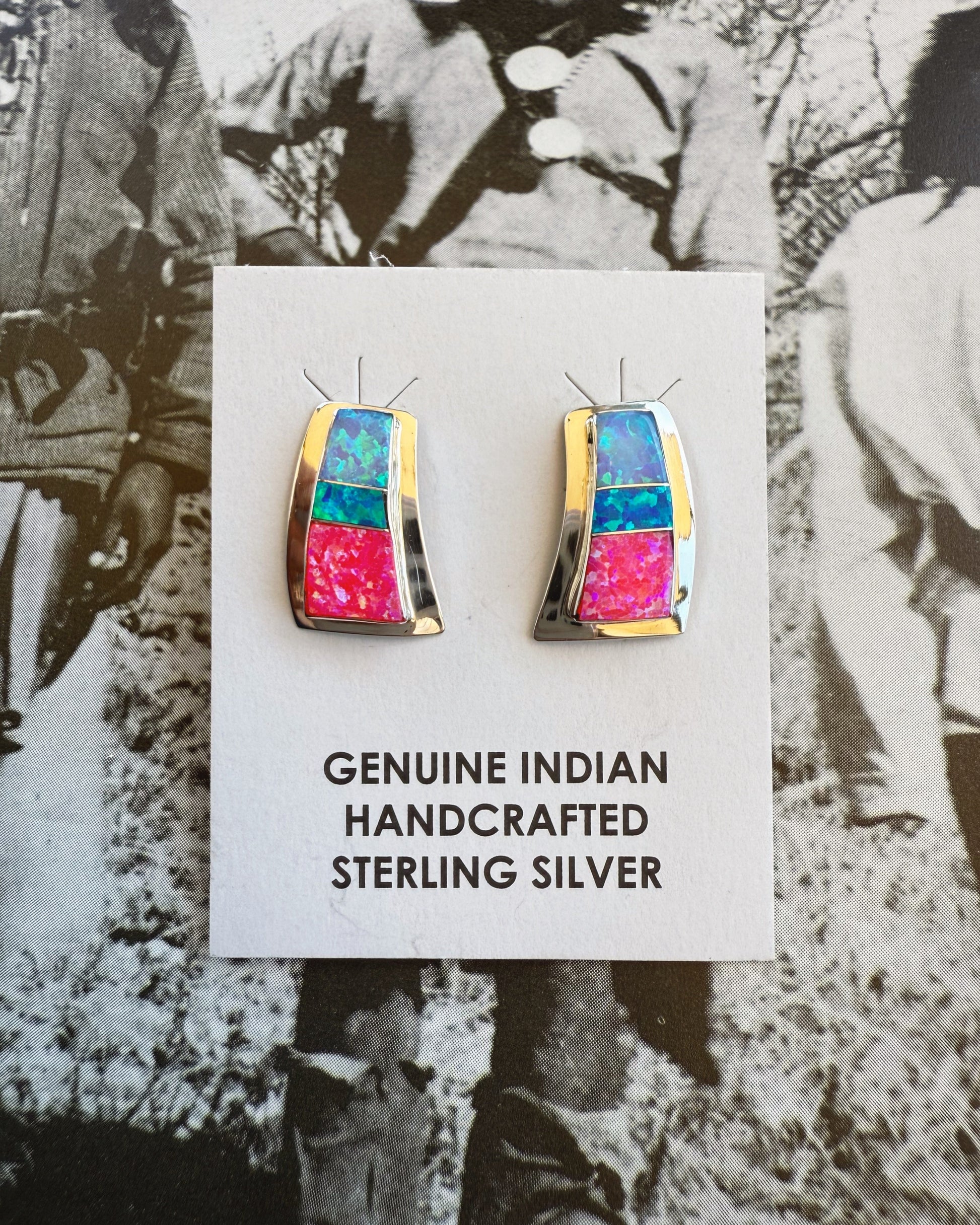 Pair of earrings with colorful design on a card labeled 'Genuine Indian Handcrafted Sterling Silver' against a vintage background.