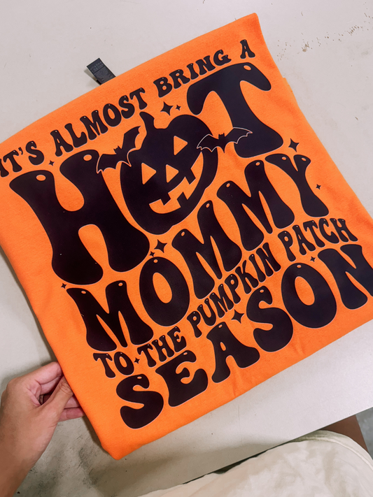 Orange Halloween-themed text and a pumpkin graphic design for t-shirt on a white surface.