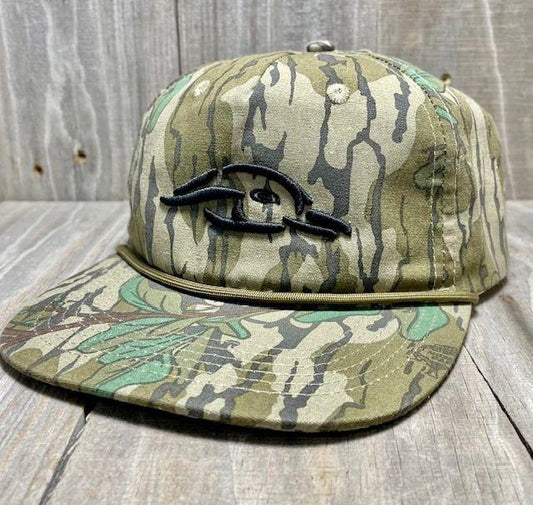 Camouflage-patterned cap with a logo on a wooden surface