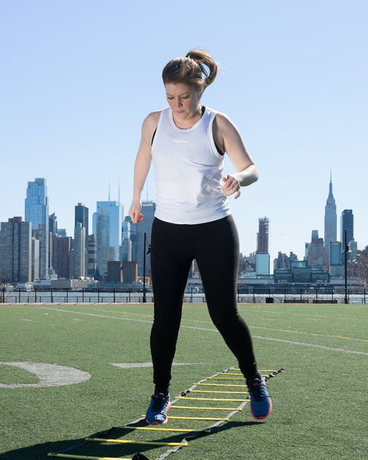 Person using a ladder for agility training with a city skyline in the background