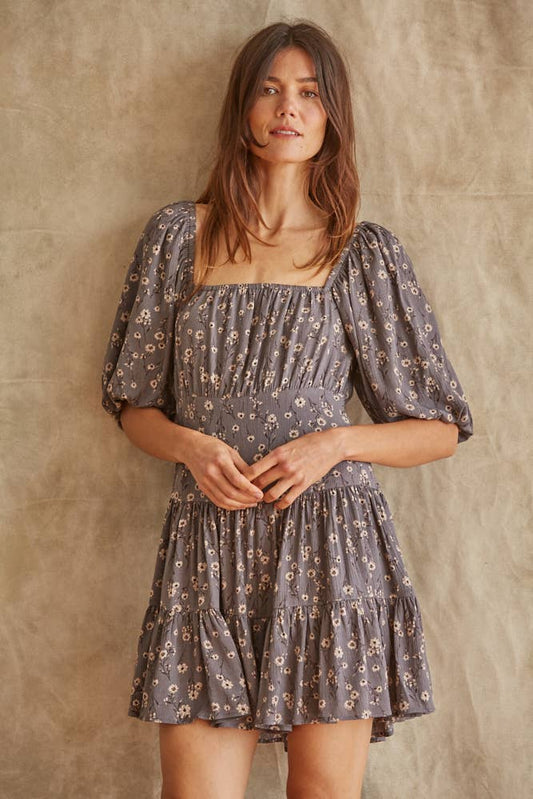 Woman wearing a floral dress against a textured wall